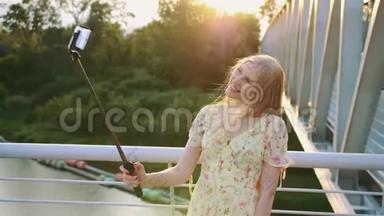 女人在桥上<strong>自拍</strong>。 站在人行桥上的一位开朗漂亮的金发女郎和monopod<strong>一起自拍</strong>